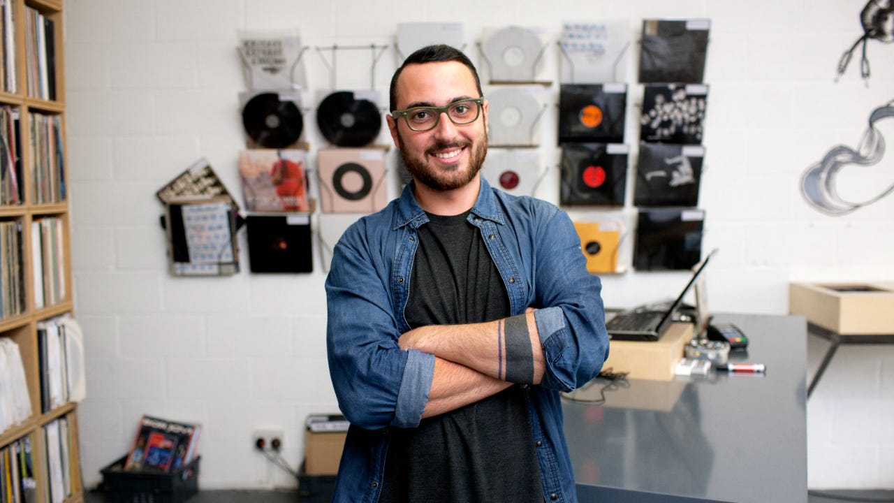 Male owner standing in front of records in his record store.