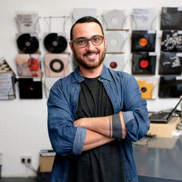 Male owner standing in front of records in his record store.