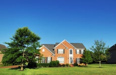 large brick single-family home, green grass blue sky