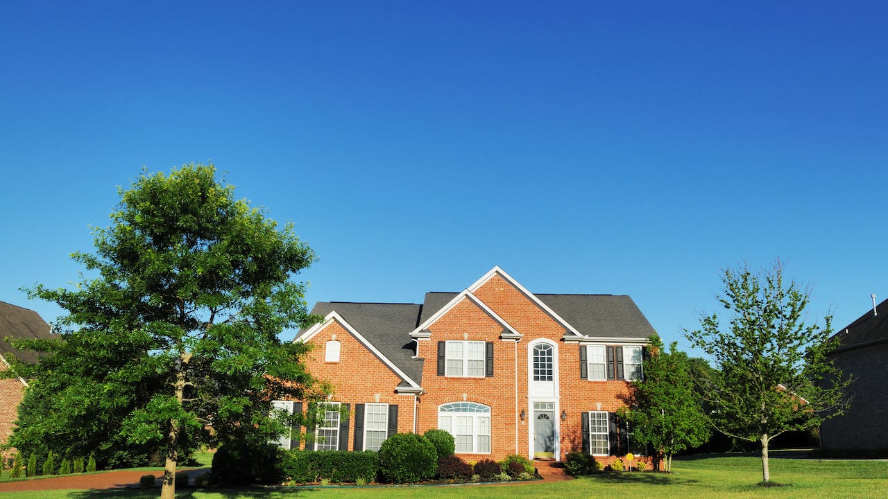 large brick single-family home, green grass blue sky