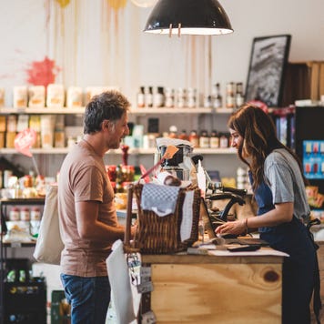 A person checks out at a register with a shop employee