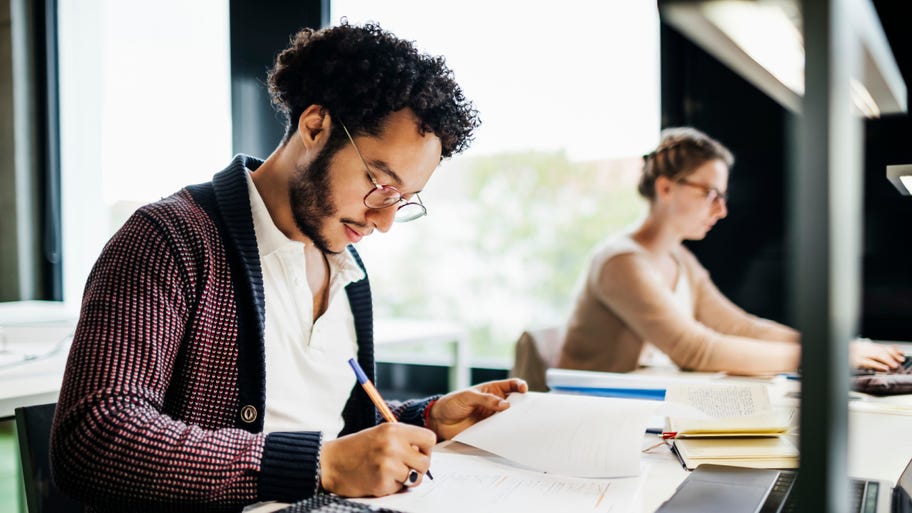 Young Student Concentrating While Studying In Public Library