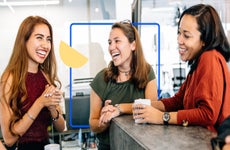 Three young adult woman chatting and laughing at a cafe
