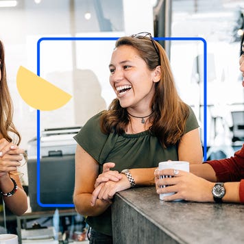 Three young adult woman chatting and laughing at a cafe
