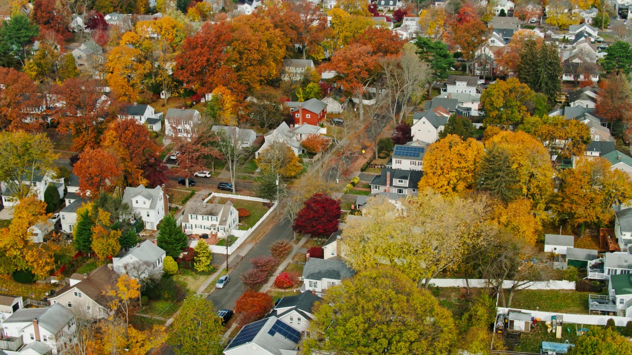Aerial shot of a residential neighborhood in Stamford, Connecticut on a sunny day in Fall, looking down on houses and vibrant autumn leaf color on the trees.