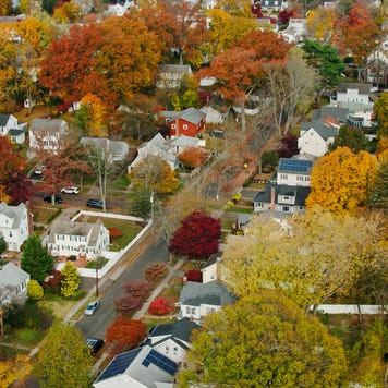 Aerial shot of a residential neighborhood in Stamford, Connecticut on a sunny day in Fall, looking down on houses and vibrant autumn leaf color on the trees.