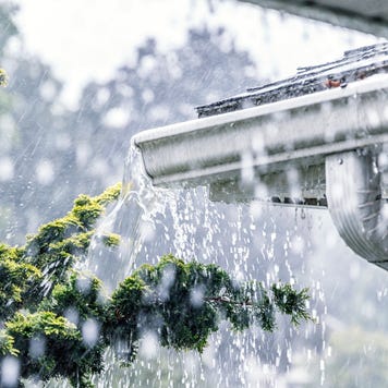 Drenching downpour rain storm water is overflowing off the tile shingle roof