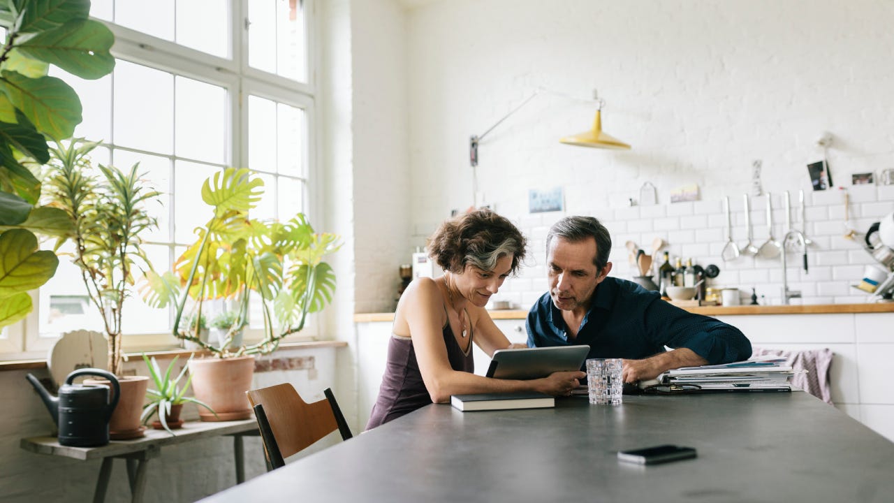 couple sitting at the breakfast table using a computer tablet