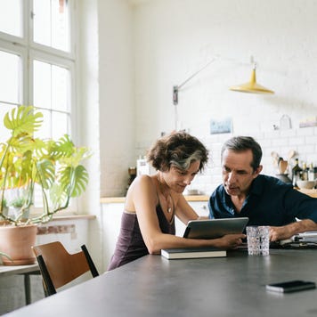 couple sitting at the breakfast table using a computer tablet