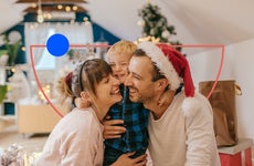 A young couple with child gathered around and laughing in front of a Christmas tree