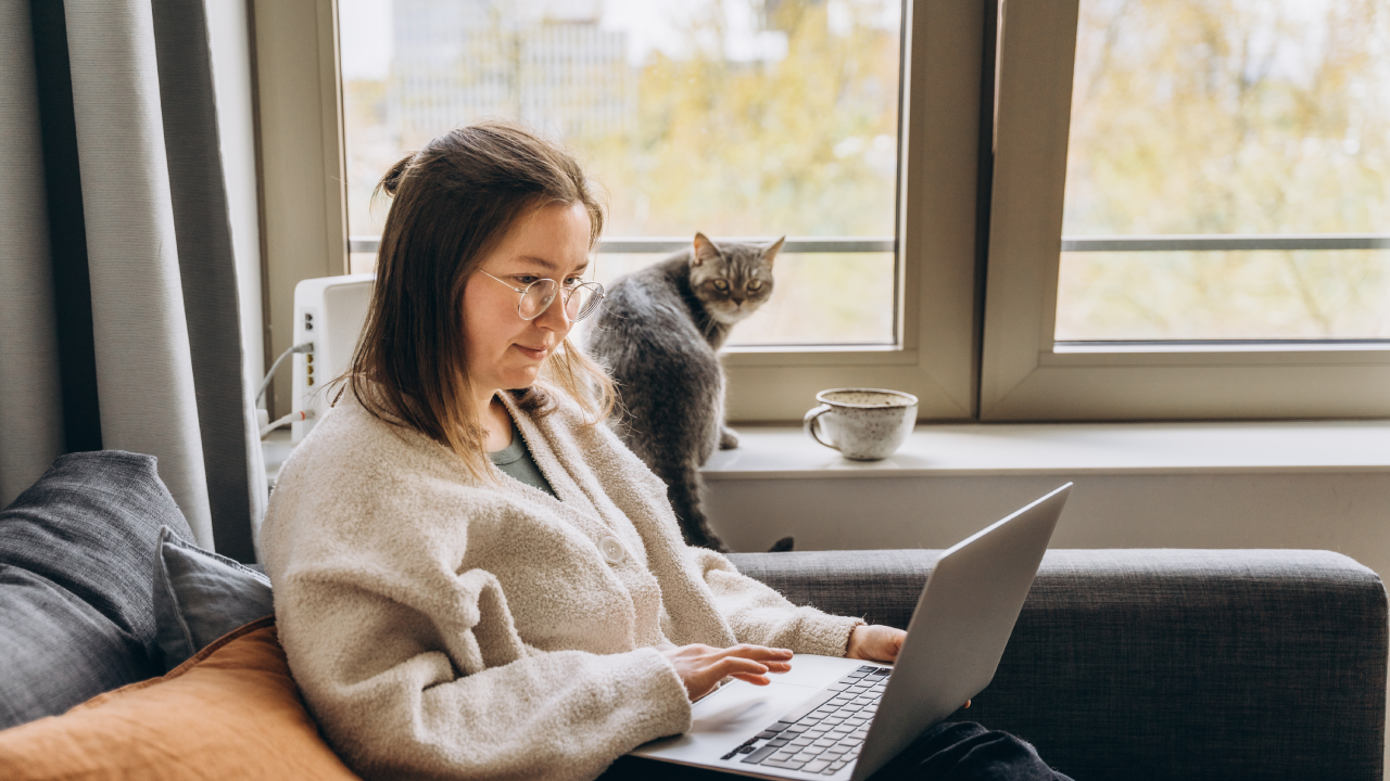 Young woman working at home remotely using a laptop while sitting on the sofa