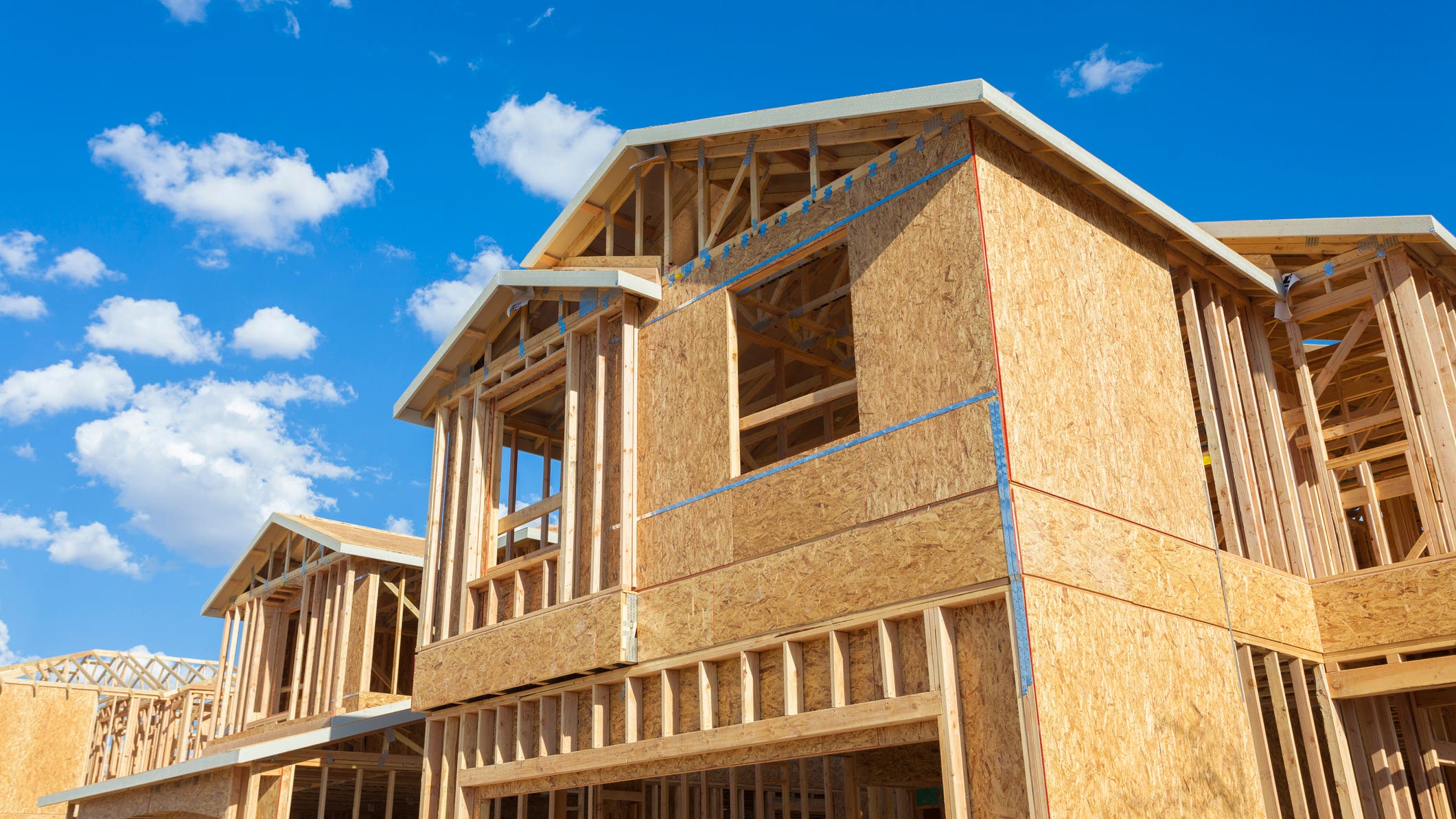 housing starts - new houses being built, wood frames against blue sky