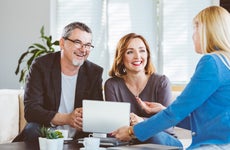 Financial advisor showing digital tablet to smiling couple at home
