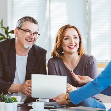 Financial advisor showing digital tablet to smiling couple at home