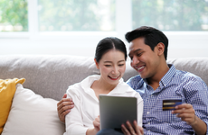 Portrait of Young Asian Couple relaxing in living room using tablet shopping online simple lifestyle in modern family