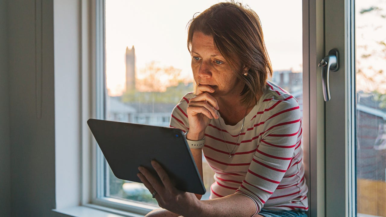 Woman using digital tablet on window sill