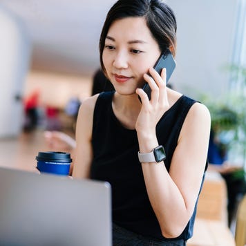 businesswoman working in a modern office space, working on laptop and taking a phone call at her desk