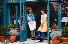 Two female business owners standing outside their shop.