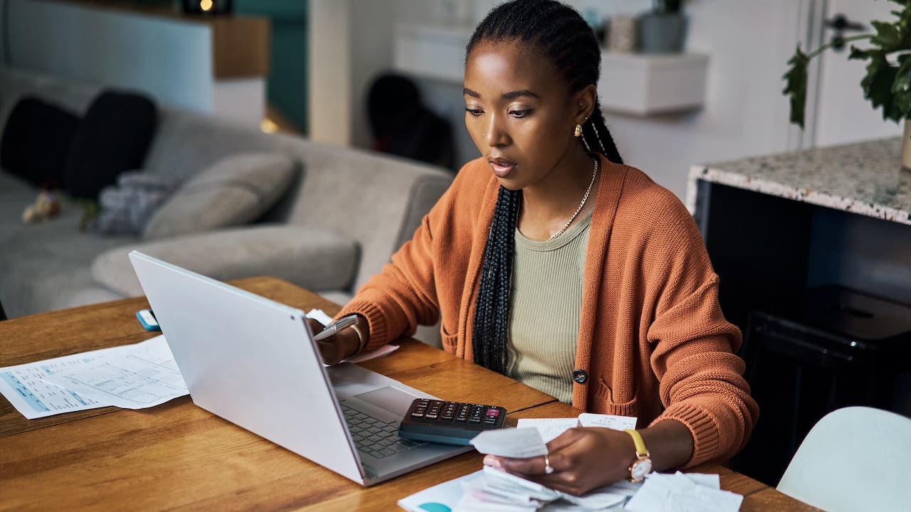 african american woman figuring out finances on laptop at home