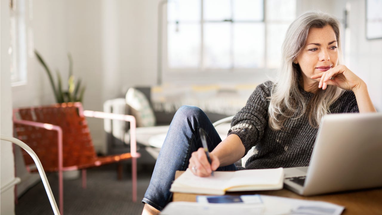 woman writing in diary while working at home