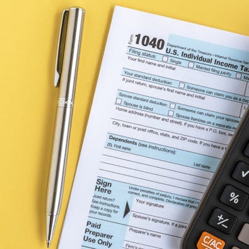 A U.S. IRS Form 1040 tax return alongside a pen and calculator