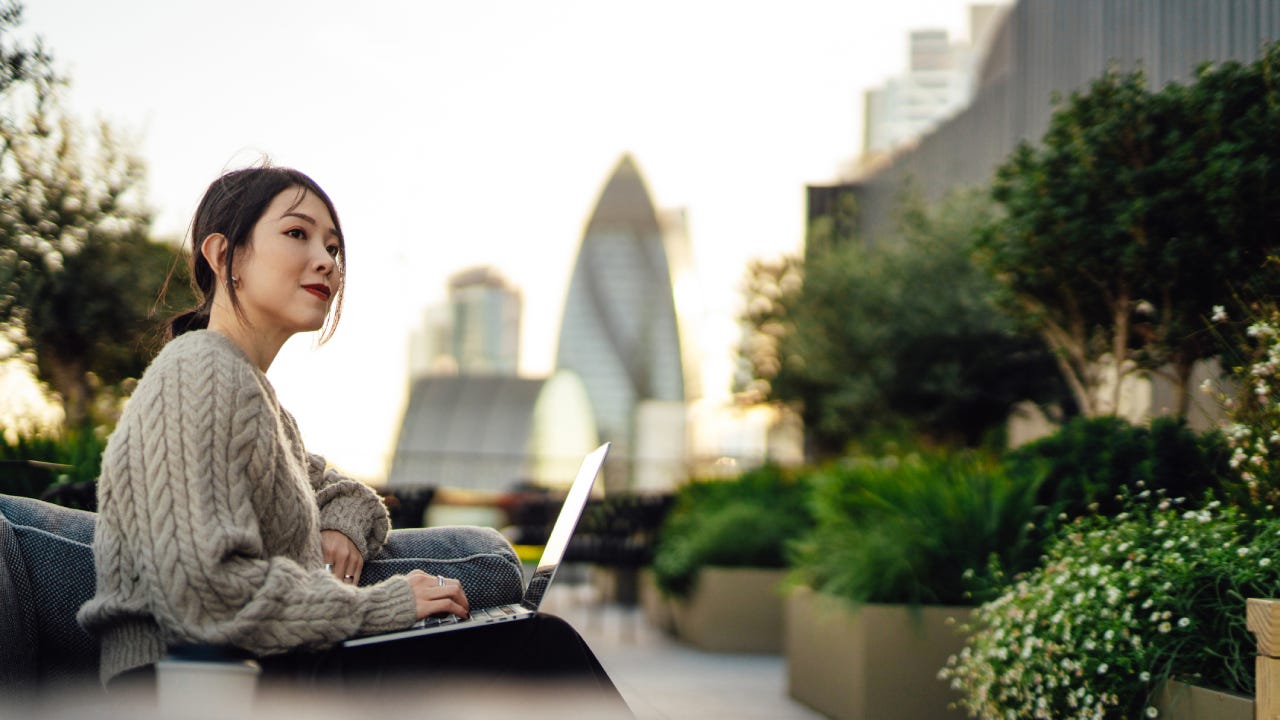 businesswoman working on laptop in rooftop garden against cityscape