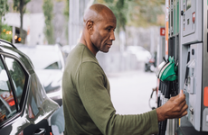 Side view of mature man doing payment through credit card while standing at gas station - stock photo