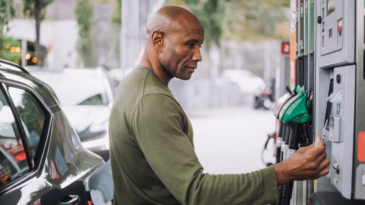 Side view of mature man doing payment through credit card while standing at gas station - stock photo