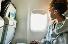 Medium shot of girl looking out window of commercial airplane while on vacation