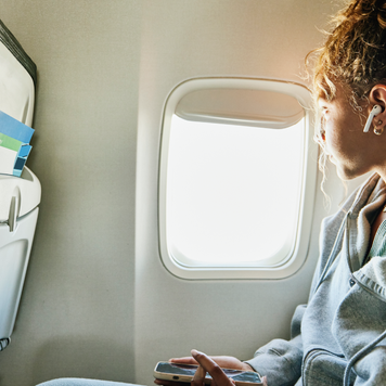 Medium shot of girl looking out window of commercial airplane while on vacation