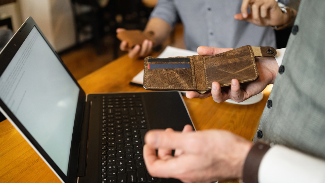 Unrecognizable businessman holding opened leather wallet, in order to pay the bill at the coffee shop for him and a friend