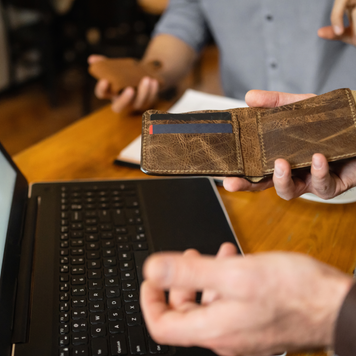 Unrecognizable businessman holding opened leather wallet, in order to pay the bill at the coffee shop for him and a friend