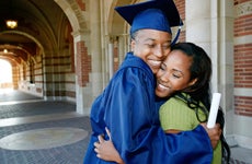 woman holding graduation diploma and hugging daughter