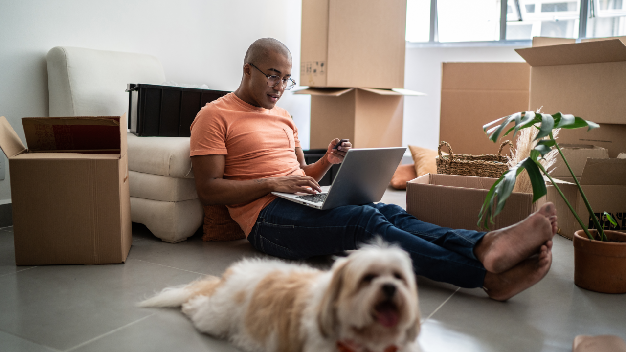 Young man doing online shopping using laptop at new home