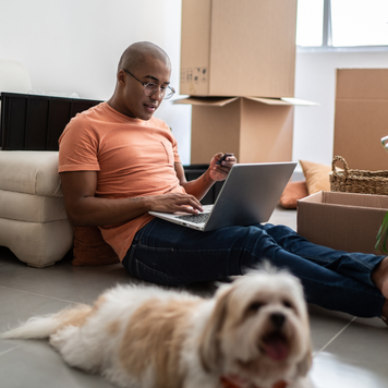 Young man doing online shopping using laptop at new home