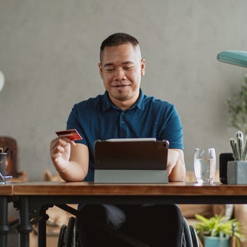 Asian man in wheelchair holding a credit card