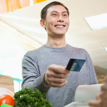 Chinese customer handing cashier credit card in grocery store