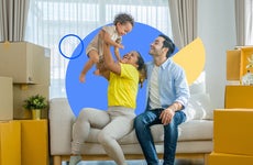Photo of a family sitting on a couch, the mom lifting a baby