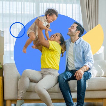 Photo of a family sitting on a couch, the mom lifting a baby