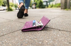 Wallet on the ground with credit cards showing and person walking away.