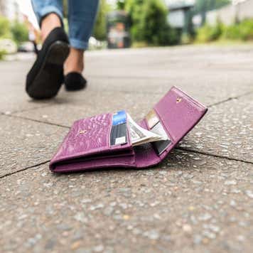 Ground-level shot of a wallet with credit cards on the ground and person walking away.