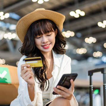 A girl using her smartphone to make a payment with a credit card.