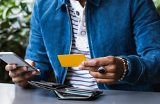 Close-up of man with credit card making mobile payment at sidewalk cafe - stock photo