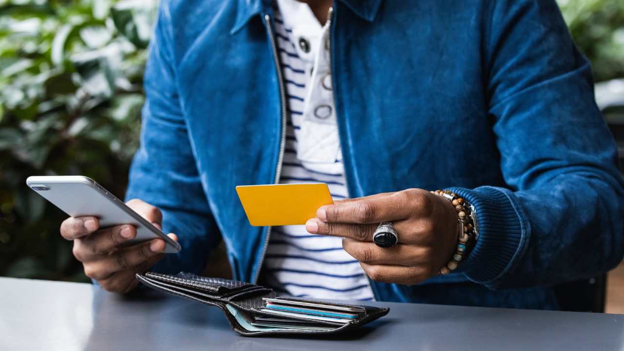 Close-up of man with credit card making mobile payment at sidewalk cafe - stock photo