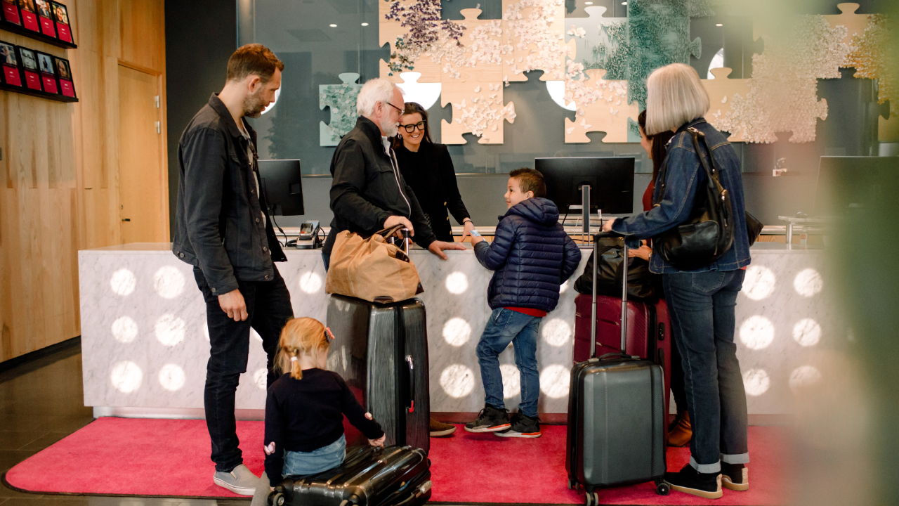 Smiling receptionist looking at boy standing with family in hotel