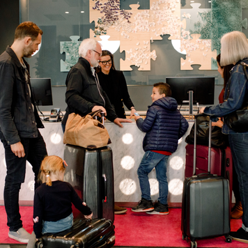 Smiling receptionist looking at boy standing with family in hotel