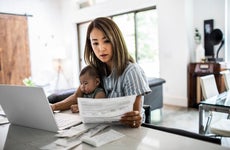 woman doing paperwork at kitchen table with baby in lap