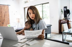 woman doing paperwork at kitchen table with baby in lap
