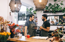 Two flower shop owners are seen actively engaged in inventory management, maintaining a well-organized and beautiful workspace.