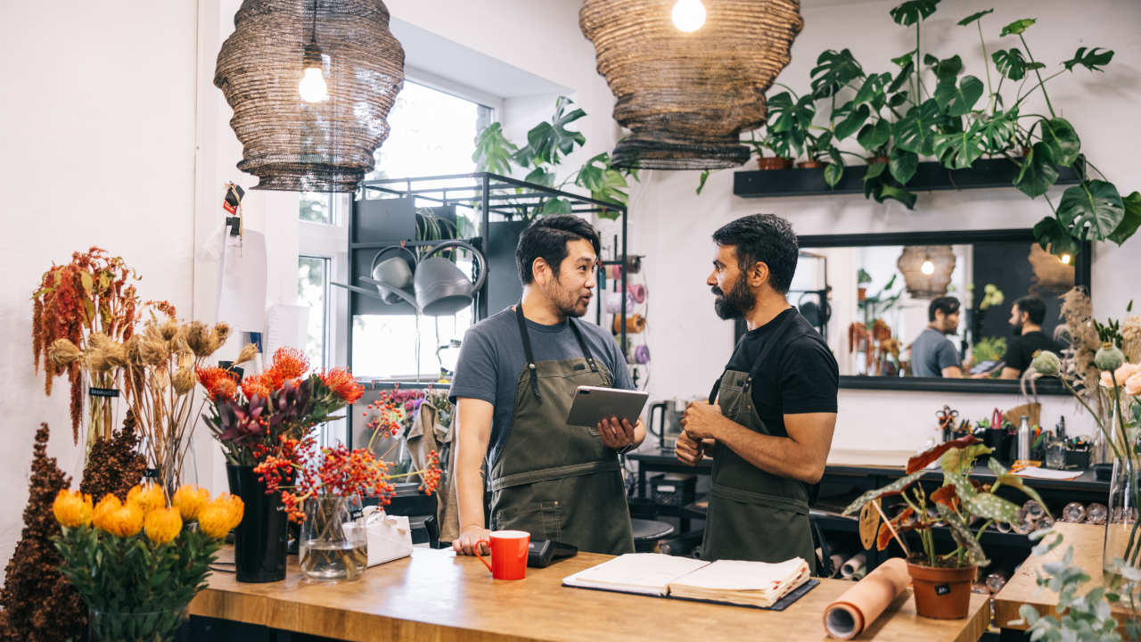 Two flower shop owners are seen actively engaged in inventory management, maintaining a well-organized and beautiful workspace.